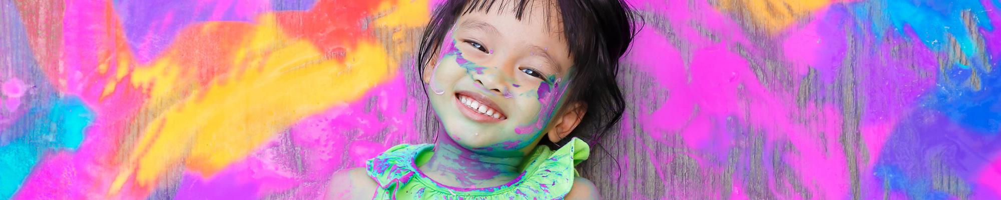 Kid covered in paint and smiling